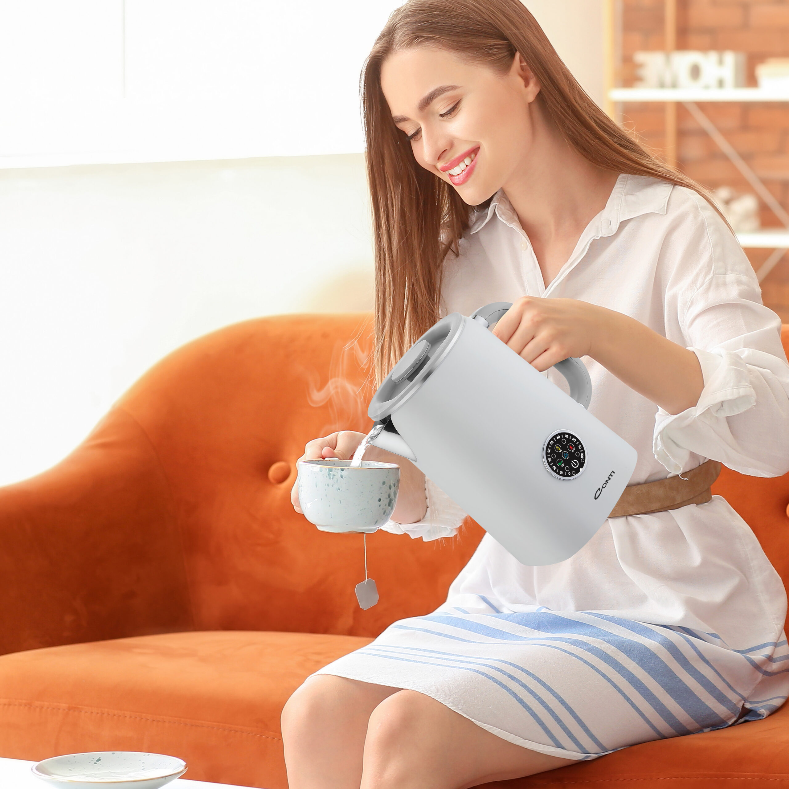 Woman pouring hot boiled water from electric kettle into cup at